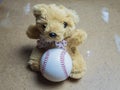 Teddy bear sitting with a baseball ball