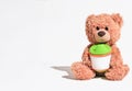 teddy bear sitting on white background and holding baby cup. kids nutrition concept, baby's first food. copy space for Royalty Free Stock Photo