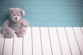 Teddy bear sitting on white wooden floor with blue-green background lonely Royalty Free Stock Photo