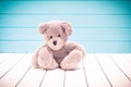 Teddy bear sitting on white wooden floor with blue-green background lonely Royalty Free Stock Photo