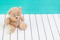 Teddy bear sitting on white wooden floor with blue-green background lonely Royalty Free Stock Photo