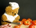 Teddy bear is slicing tomatoes Royalty Free Stock Photo