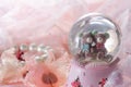 Teddy bear in snow globe decoration on pink fabric background. Royalty Free Stock Photo