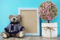 Teddy bear and space photo frame with artificial plant home decoration on blue