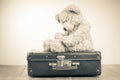 Teddy Bear toy alone on suit case. Vintage style sepia photo