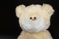 Teddy bear toy in a protective medical mask on a black Royalty Free Stock Photo