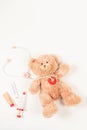 Teddy bear with toy stethoscope and wooden toy medicine tools on a white background. Top view. Concept of children's Royalty Free Stock Photo