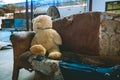 Teddy bear on a vintage sofa in an industrial building Royalty Free Stock Photo