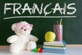 Teddy bear wearing glasses in a French language classroom next to an apple and a pile of books and a dictionary Royalty Free Stock Photo