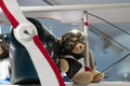 Teddy bear wearing pilot glasses and a pilot`s jacket on the wing of a vintage aircraft. close up