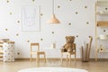 Teddy bear on wooden chair next to table in gold kid`s room inte Royalty Free Stock Photo