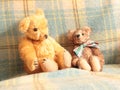 Two teddy bears handmade sitting on blue rug.