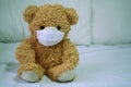 Teddy bears are sick, wearing a mask, sitting on a white bed with loneliness and loneliness. Coronavirus Covid-19 and pm2.5, stay