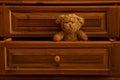 Teddy brown bear sits in a wooden pull-out old drawer in the bedroom as a background,furniture Royalty Free Stock Photo