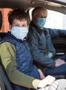 Teen age child with his father wearing medical mask inside the car, young boy and senior man