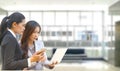 Teen age worker holding mobile phone in hand talk to senior worker working with laptop while the woman serious about inter net can Royalty Free Stock Photo