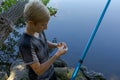 The teen angler checks the bait and puts a new one on. Sport fishing on the river in summer Royalty Free Stock Photo