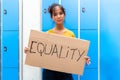 Teen asian girl looking at camera carrying an vindictive equality sign banner in high school