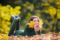 Teen in the autumn park. Smiling young girl lying on autumn maple leaves at fall outdoors. Portrait of a beautiful Royalty Free Stock Photo