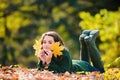 Teen in the autumn park. Smiling young girl lying on autumn maple leaves at fall outdoors. Portrait of a beautiful Royalty Free Stock Photo