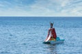 Teen in bathing suit sitting with hands up in the air on paddleboat with slide at beach