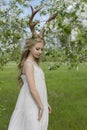 Teen beautiful blonde girl wearing white dress with deer horns o