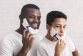 Teen Black Guy Shaving Together With Dad, Holding Rasor In Bathroom Royalty Free Stock Photo