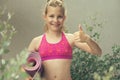 Teen blonde girl holding yoga mat and showing thumb up sign