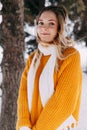 Teen blonde in a yellow sweater outside in winter. A teenage girl on a walk in winter clothes in a snowy forest Royalty Free Stock Photo