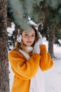 Teen blonde in a yellow sweater outside in winter. A teenage girl on a walk in winter clothes in a snowy forest Royalty Free Stock Photo