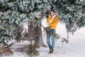 Teen blonde in a yellow sweater outside in winter. A teenage girl on a walk in winter clothes in a snowy forest Royalty Free Stock Photo