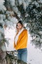 Teen blonde in a yellow sweater outside in winter. A teenage girl on a walk in winter clothes in a snowy forest Royalty Free Stock Photo