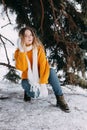 Teen blonde in a yellow sweater outside in winter. A teenage girl on a walk in winter clothes in a snowy forest Royalty Free Stock Photo