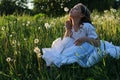 Teen blowing seeds from a dandelion flower in a spring park Royalty Free Stock Photo