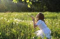 Teen blowing seeds from a dandelion flower in a spring park Royalty Free Stock Photo