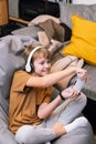 Teen boy actively and recklessly playing video game with joystick sitting on frameless beanbag chair Royalty Free Stock Photo