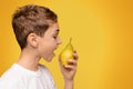 Teen boy biting fresh pear, side view Royalty Free Stock Photo