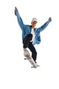 Teen boy in blue jeans shirt and cap in motion, training with skateboard, doing stunts isolated over white background Royalty Free Stock Photo