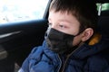 A teen boy in car wearing surgical medical black face mask as a protection against virus disease Royalty Free Stock Photo