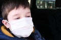 A teen boy in car wearing white surgical medical face mask as a protection against virus disease Royalty Free Stock Photo