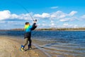 Teen boy catching a fish with fishing rod on beach. Boy throws rod to the river Royalty Free Stock Photo