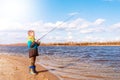 Teen boy catching a fish with fishing rod on beach. Boy throws rod to the river Royalty Free Stock Photo