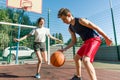 Teen boy coaching his girlfriend playing basketball, street basketball game