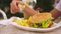 Teen boy eating hamburger and french fries in outdoor cafe. close-up Royalty Free Stock Photo