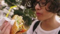 Teen boy eating hamburger and french fries in outdoor cafe. close-up Royalty Free Stock Photo