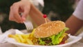 Teen boy eating hamburger and french fries in outdoor cafe. close-up Royalty Free Stock Photo