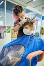 Teen boy in face mask doing haircut at barber shop Royalty Free Stock Photo