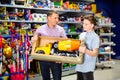 Teen boy with father visiting children toy store in search of big plastic car for gift