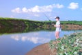 Teen boy is fishing in river using spinning rod at summer sunny day on nature. Royalty Free Stock Photo