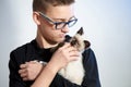 Teen boy in glasses with a Siamese Thai kitten